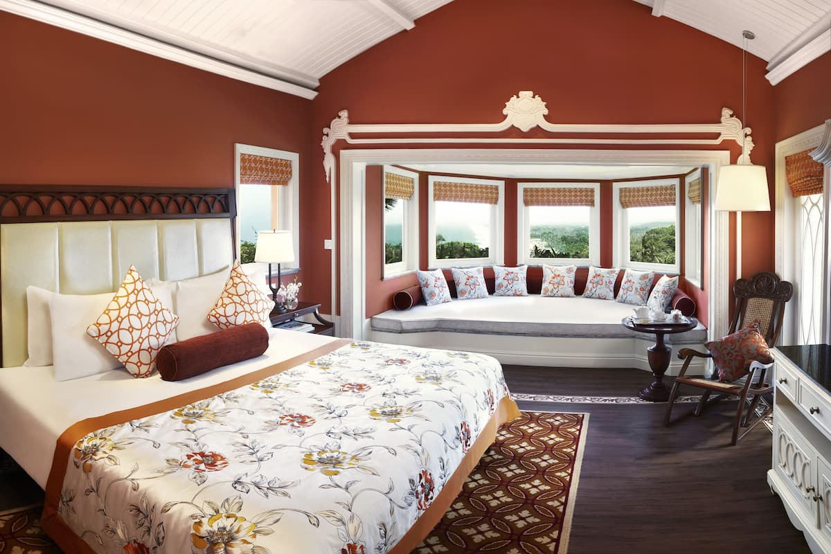 A hotel room with a large bed, a seating area with a view, and a dining table.