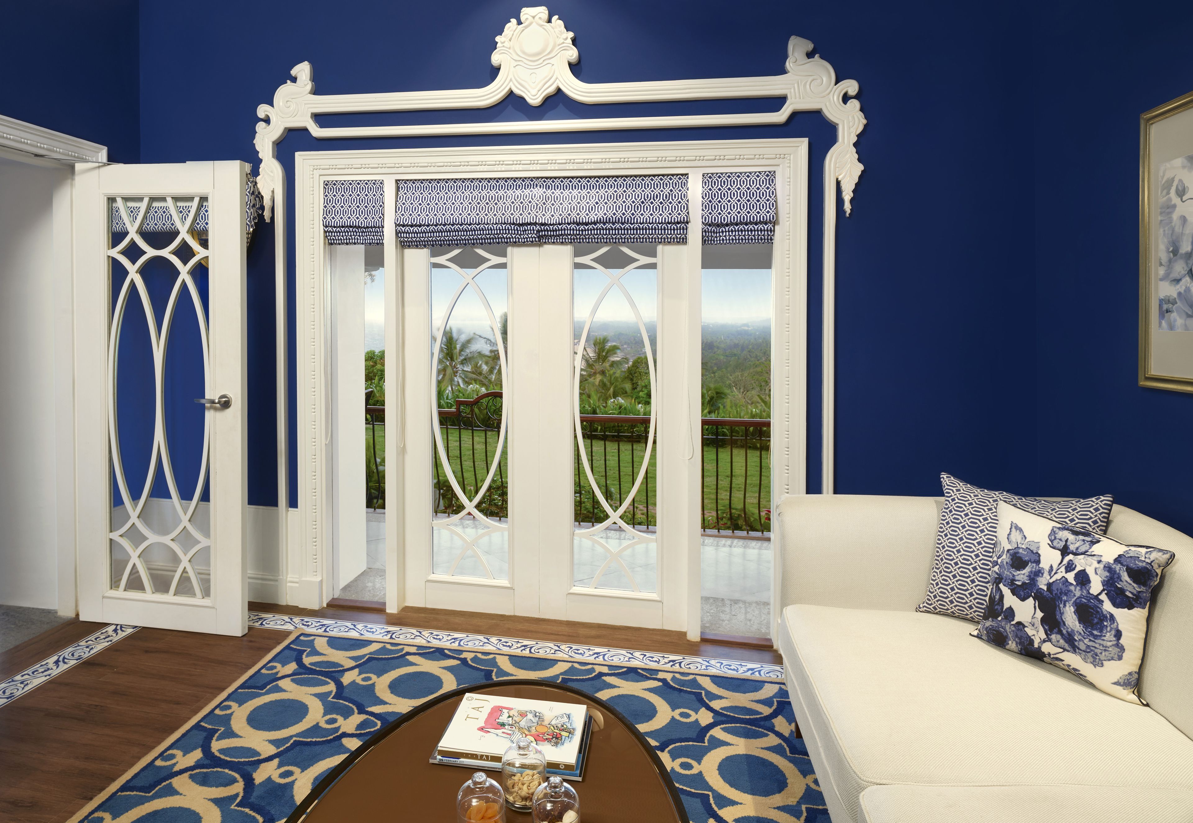 A room with a blue wall, white doors, a beige sofa, and patterned floor runner.
