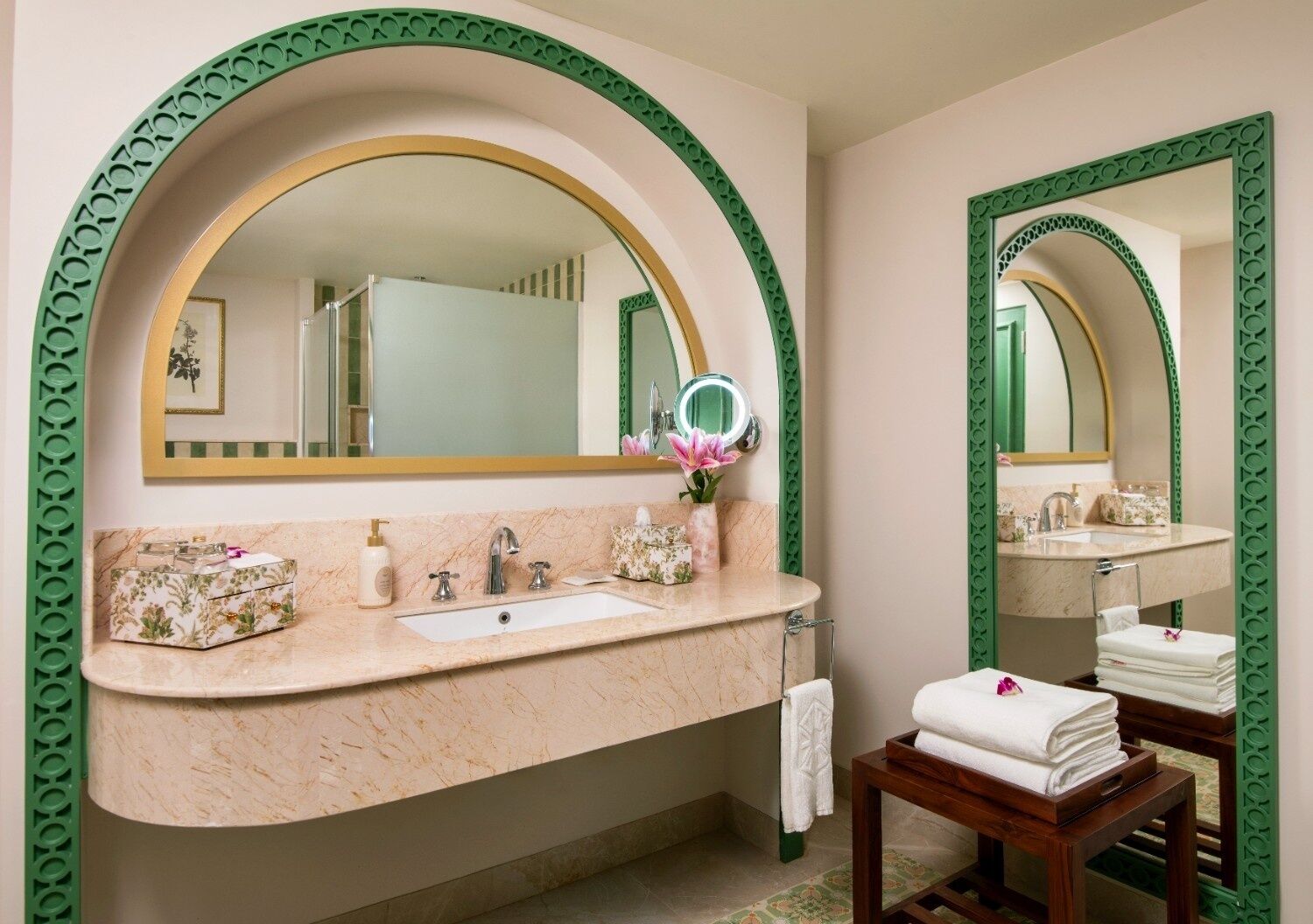 Une salle de bain avec un meuble-lavabo en marbre, un grand miroir et une bordure décorative verte.