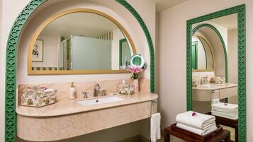 Une salle de bain avec un meuble-lavabo en marbre, un grand miroir et une bordure décorative verte.