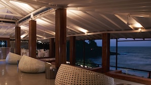 A spacious indoor area with large windows overlooking the ocean, featuring modern seating and a bar area. - Taj Fort Aguada Resort & Spa, Goa (Candolim)