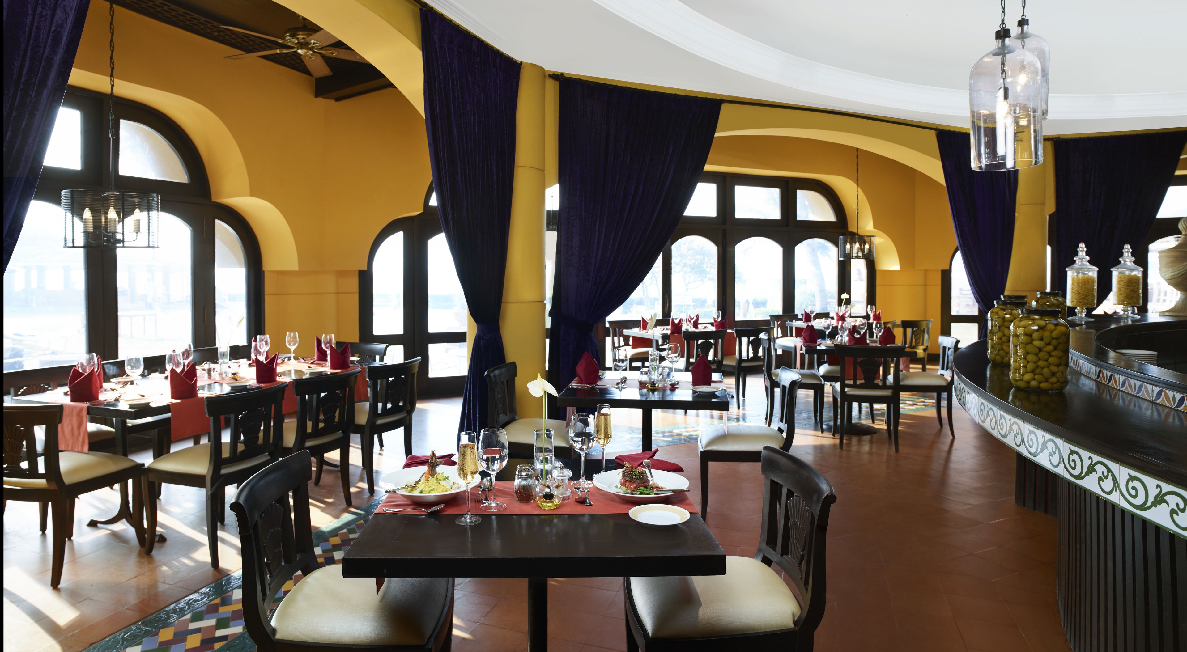 A restaurant with multiple tables set for dining, featuring a mix of chairs and benches.