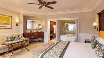 Une chambre d’hôtel comprenant un lit, un coin salon avec une table et des chaises, une coiffeuse avec un miroir et un ventilateur de plafond.