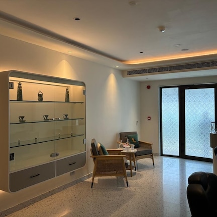 A modern hotel lobby with a glass display case, seating area, and large windows.