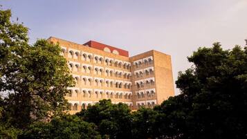 A multi-story building with a series of arches on the facade, surrounded by trees.