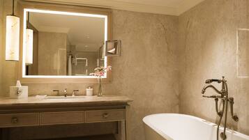 A bathroom with a large mirror, a bathtub, a vanity with drawers, and a towel rack.