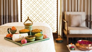 Un ambiente de spa con una cama, una bandeja de productos de baño y una silla.