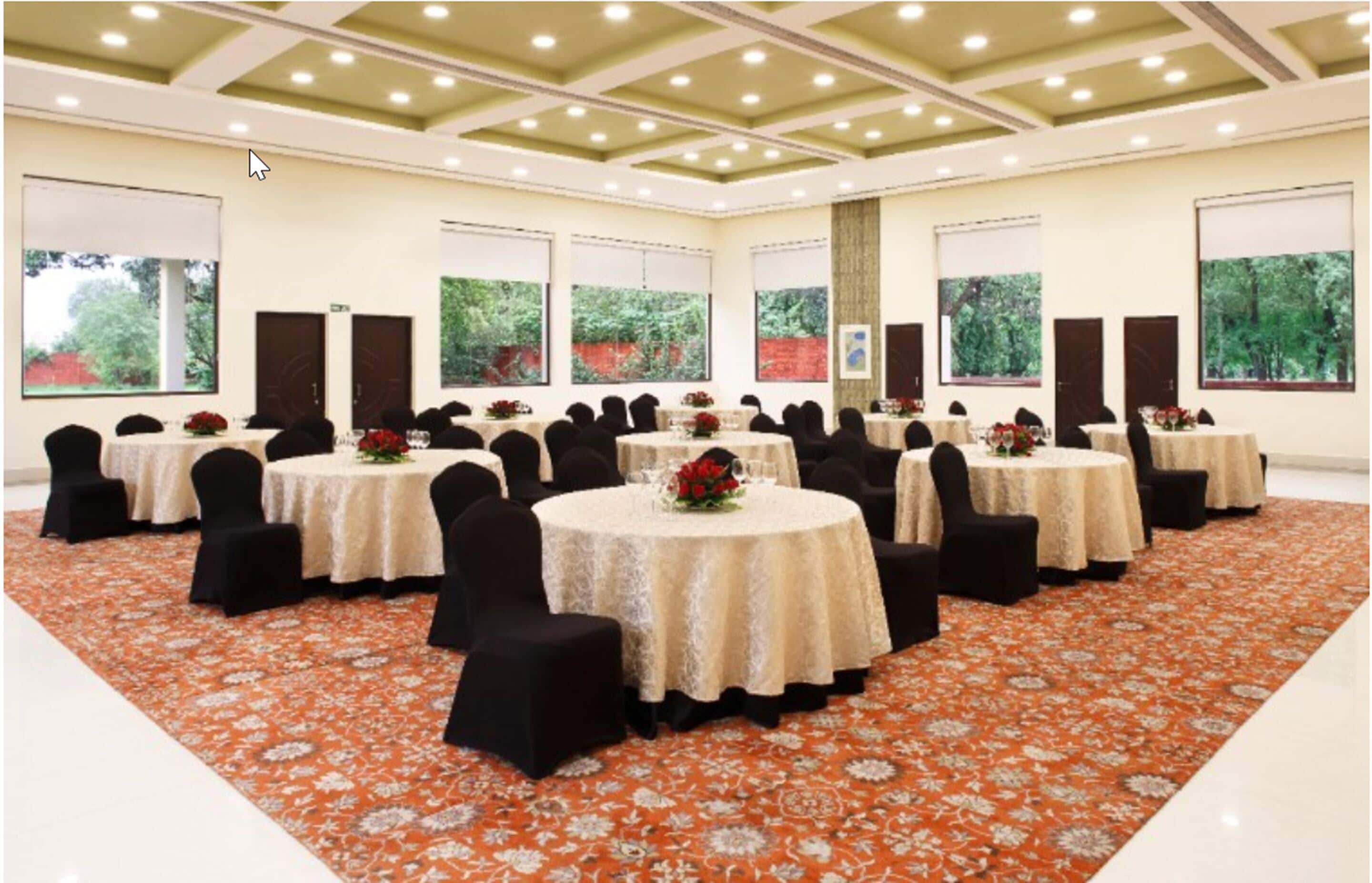 Une salle de conférence avec des tables rondes, des chaises noires et un tapis à motifs.