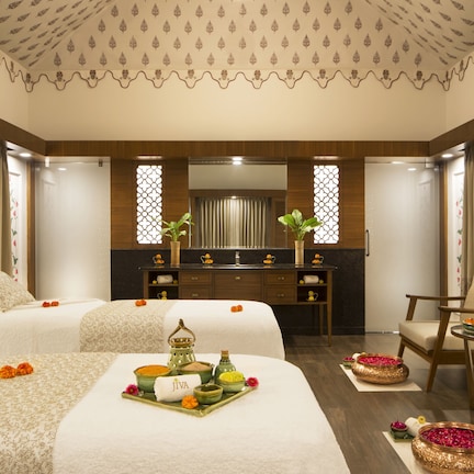 A hotel room with two beds, a sitting area with a chair, a small table, and a decorative tray with toiletries.