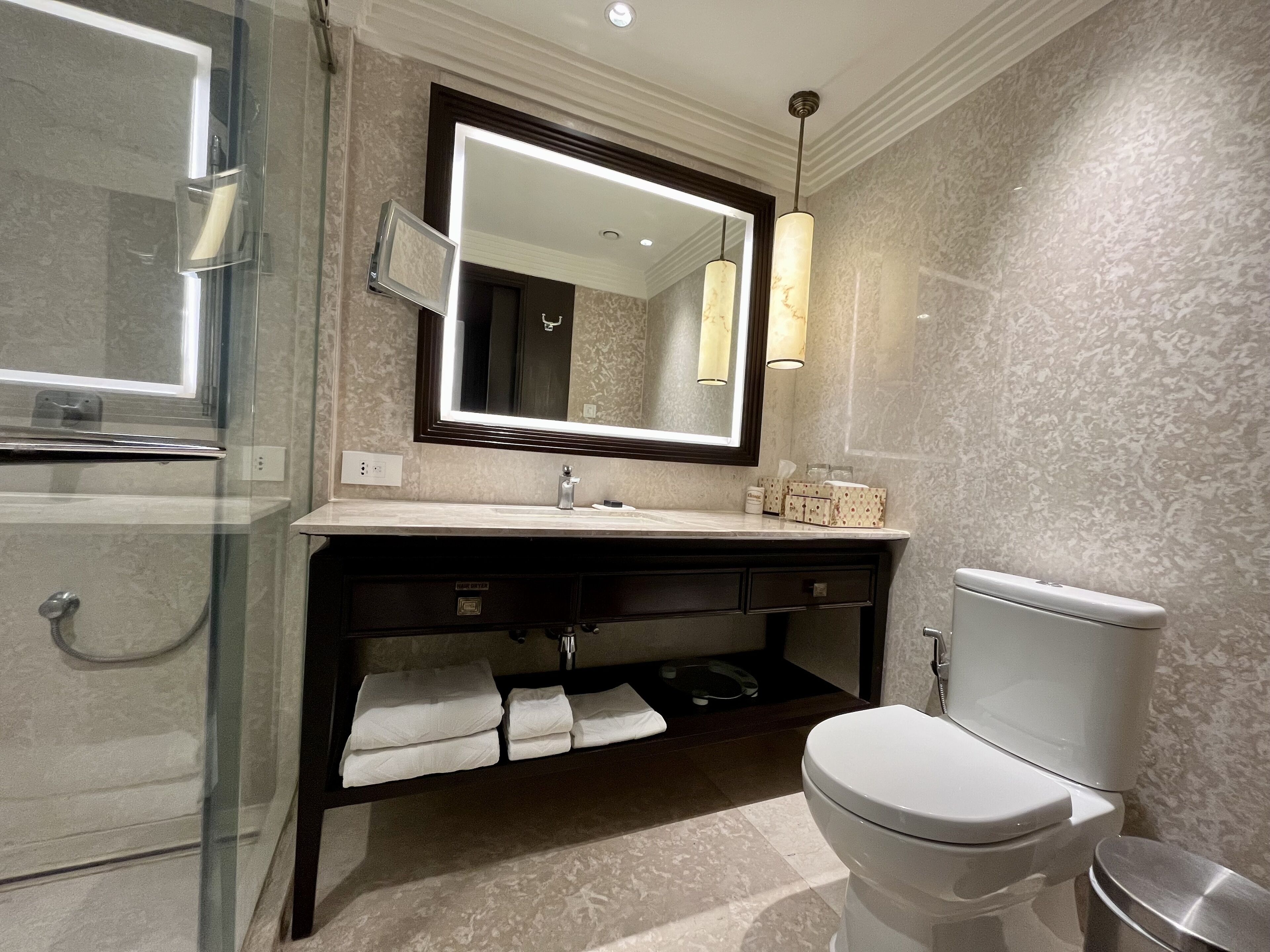 A modern bathroom with a large mirror, a vanity with a sink, and a toilet.