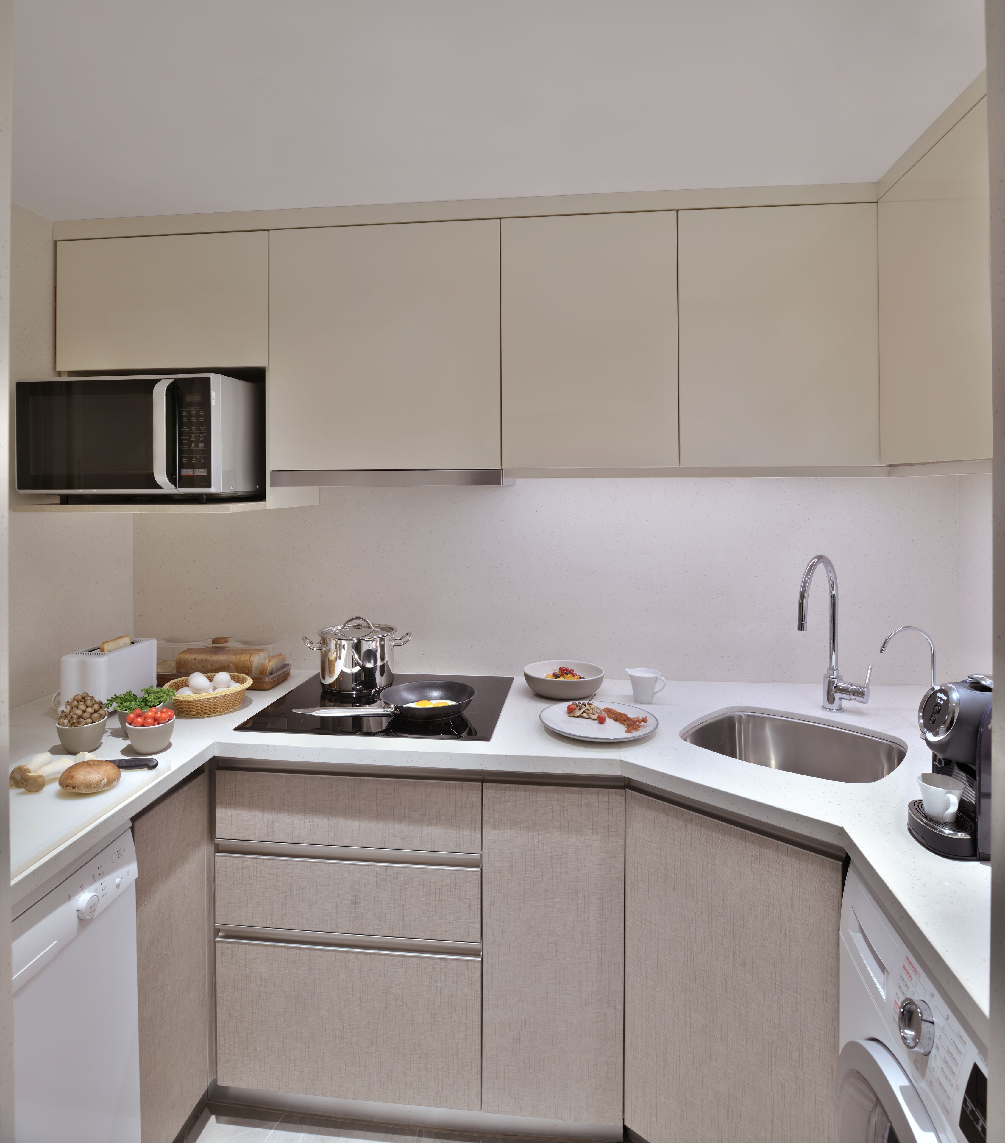 A compact kitchen with a microwave, stove, sink, and built-in cabinets.