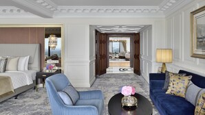 A hotel room with a large bed, a blue armchair, a blue sofa, a round coffee table with flowers, and a chandelier. - Taj Mahal, New Delhi (New Delhi)