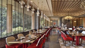 A spacious restaurant with long tables, red chairs, and hanging light fixtures. - Taj Mahal, New Delhi (New Delhi)