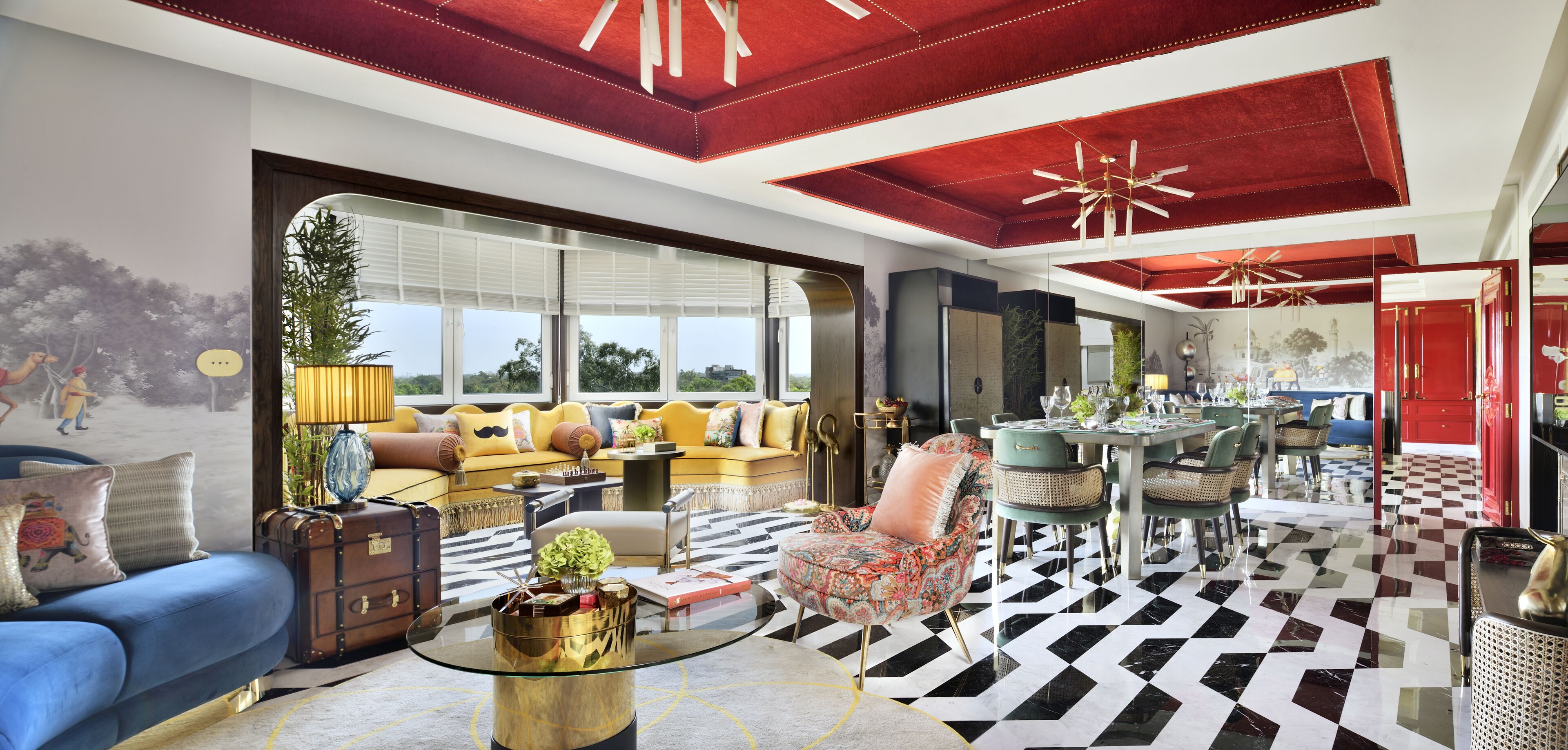 A spacious living room with a large sofa, a coffee table, and a dining area with a checkered floor.
