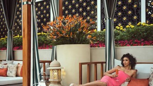 A person reclining on a white sofa with cushions, a potted plant with orange flowers, and a lantern on a table. - Taj Mahal, New Delhi (New Delhi)