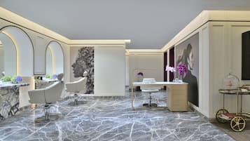 A modern bathroom with marble flooring, a vanity with a sink, and two chairs.