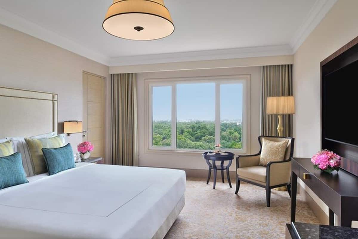 A hotel room with a large bed, a desk, a chair, a television, and a window with a view.