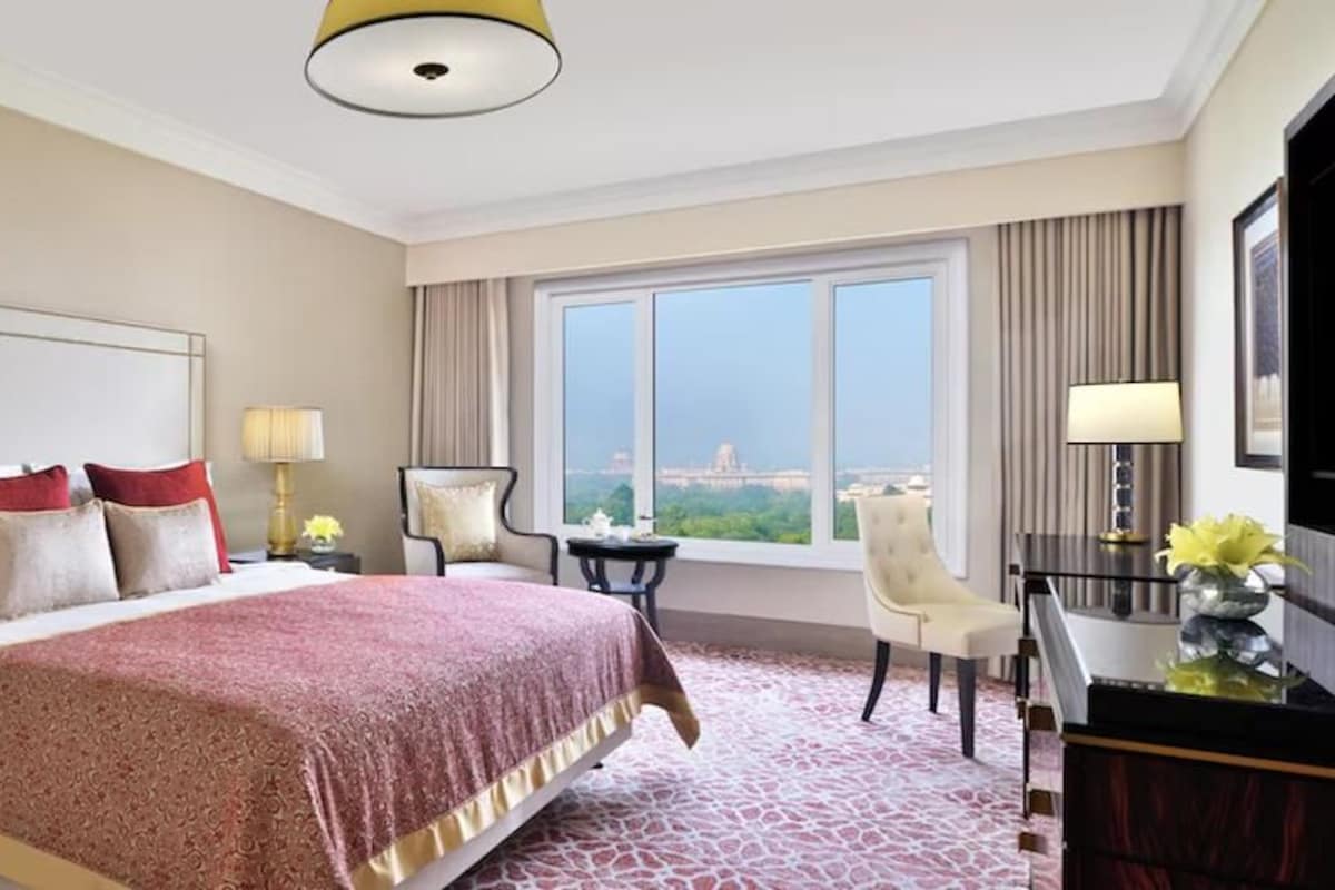 A hotel room with a large bed, a desk, a chair, and a view of the city.