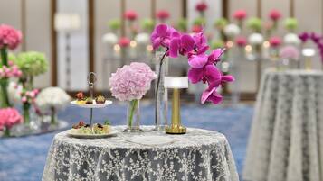 A table with a floral arrangement, a vase, and a small dessert stand.