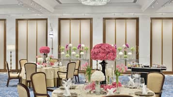 A formal dining room with tables set for service, a chandelier, and traditional decor.