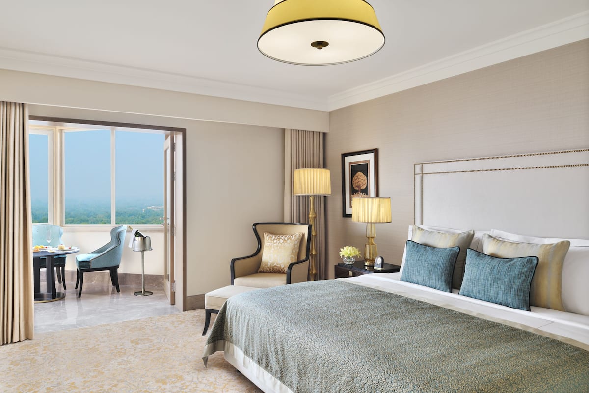 Habitación de hotel con cama, escritorio, silla, televisor y vistas al exterior.