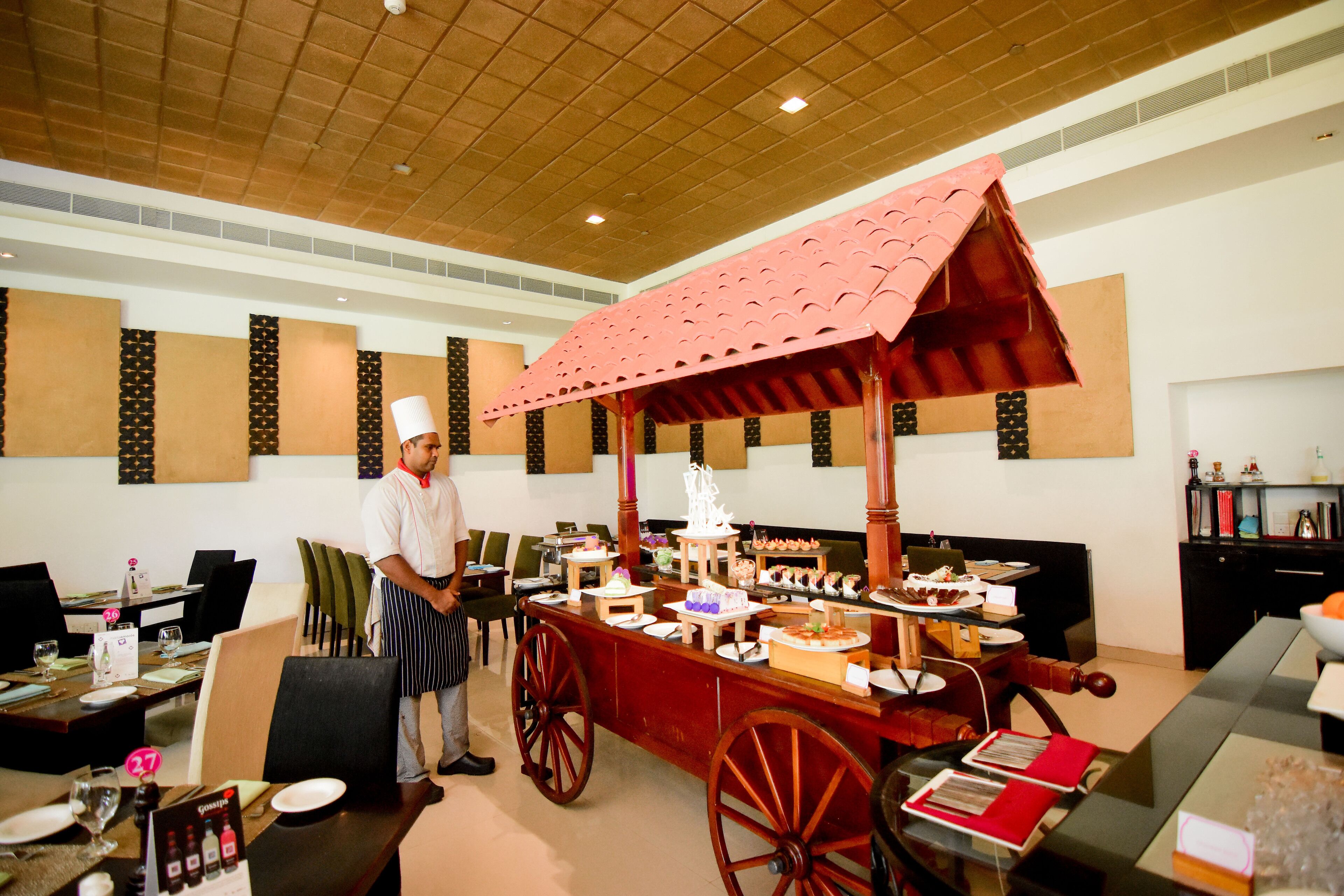 A buffet setup with a chef, a red canopy, and a variety of food items.