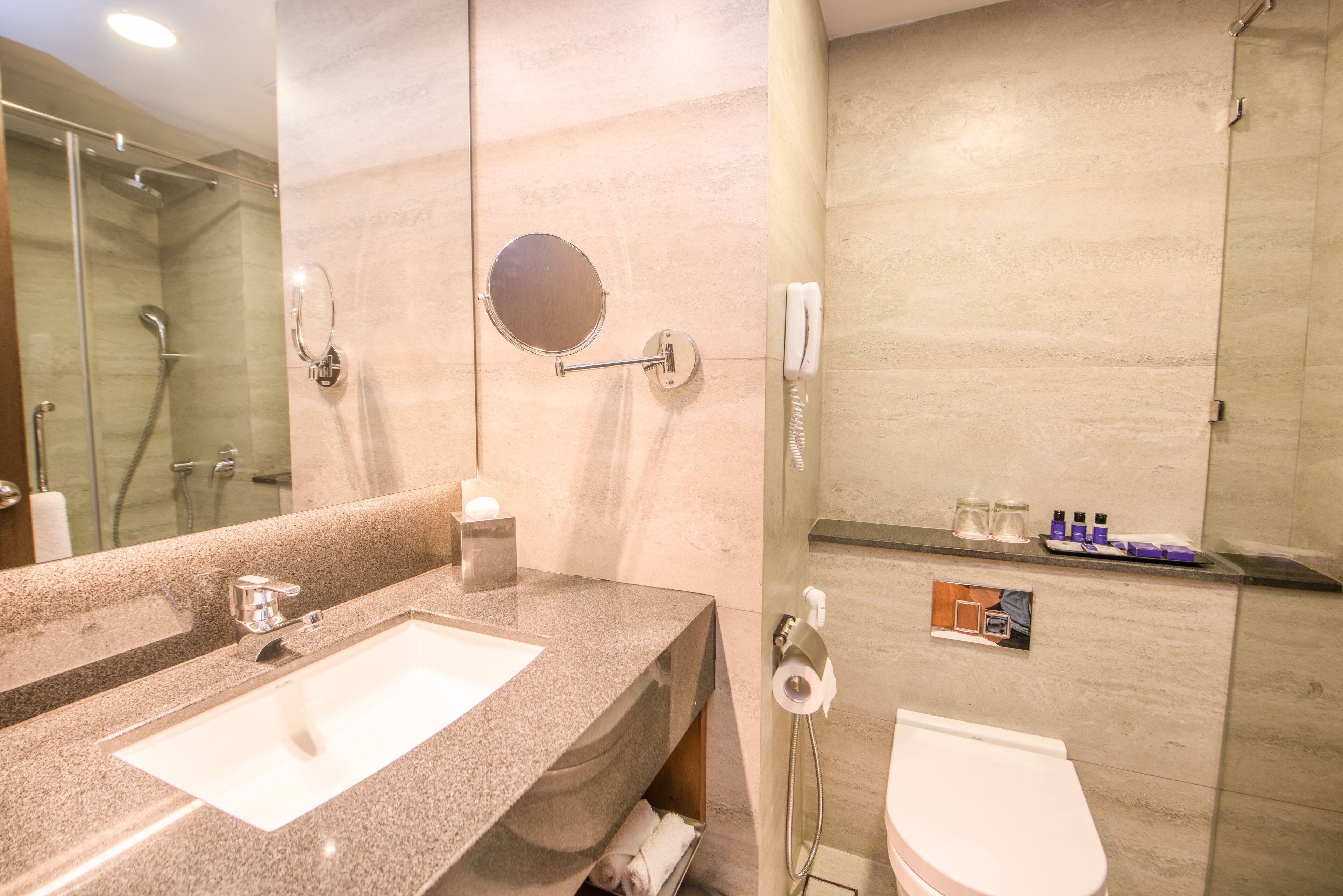 Un baño con lavamanos doble, inodoro, cabina de ducha de vidrio y espejo.