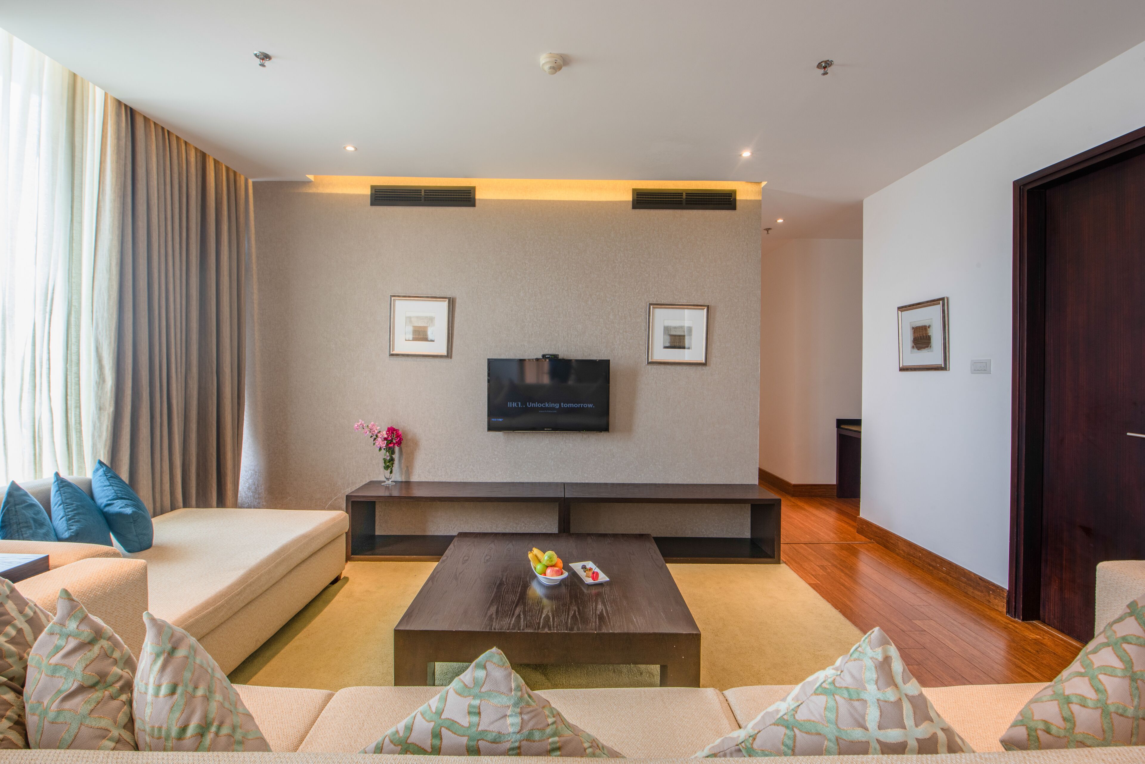A modern living room with a sofa, coffee table, and a flat-screen TV mounted on the wall.