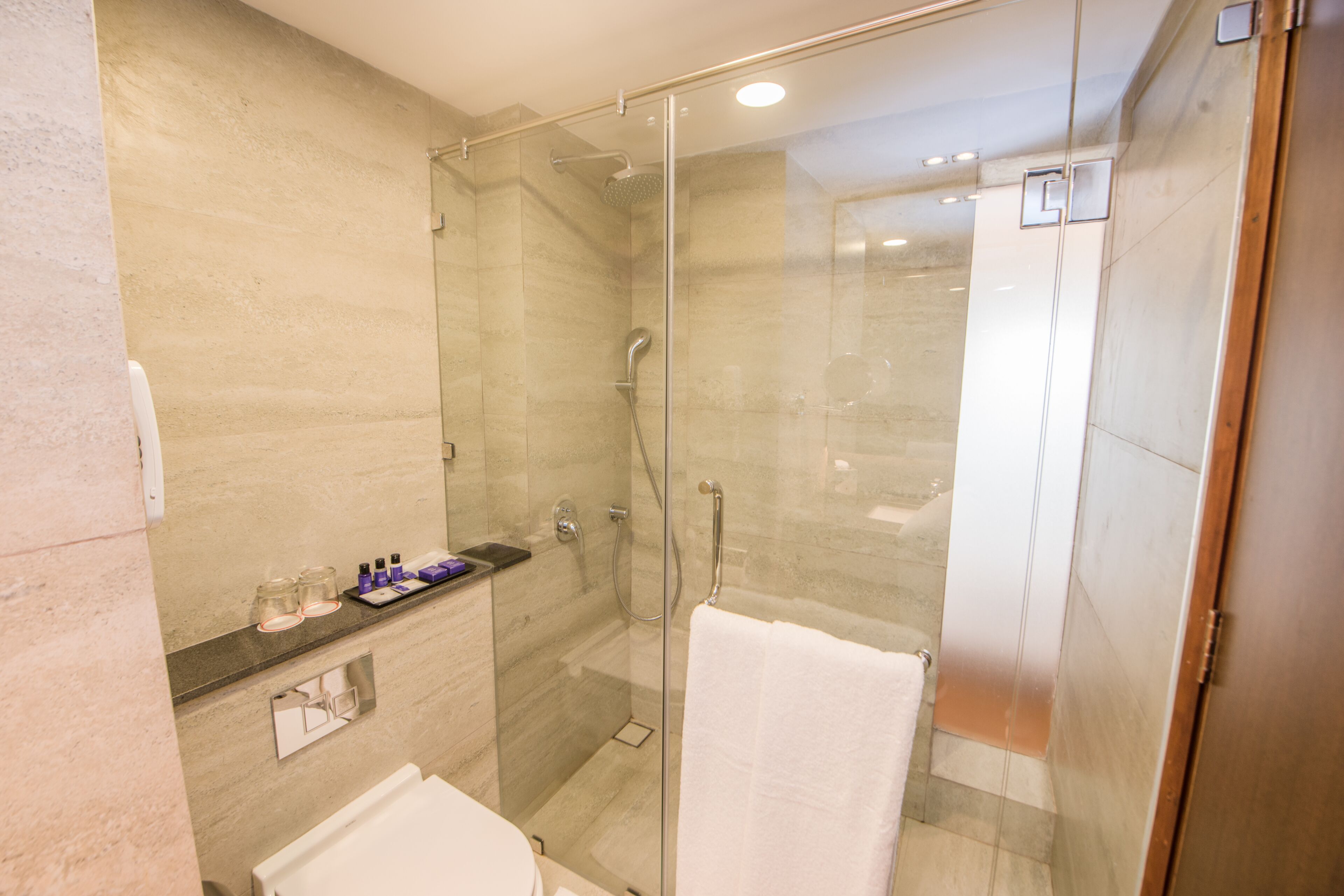 Un baño moderno con ducha de vidrio, lavamanos blanco y un espejo.