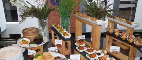 Un buffet proposant divers plats, notamment des nems, des pinces de crabe et des rouleaux de printemps aux légumes.