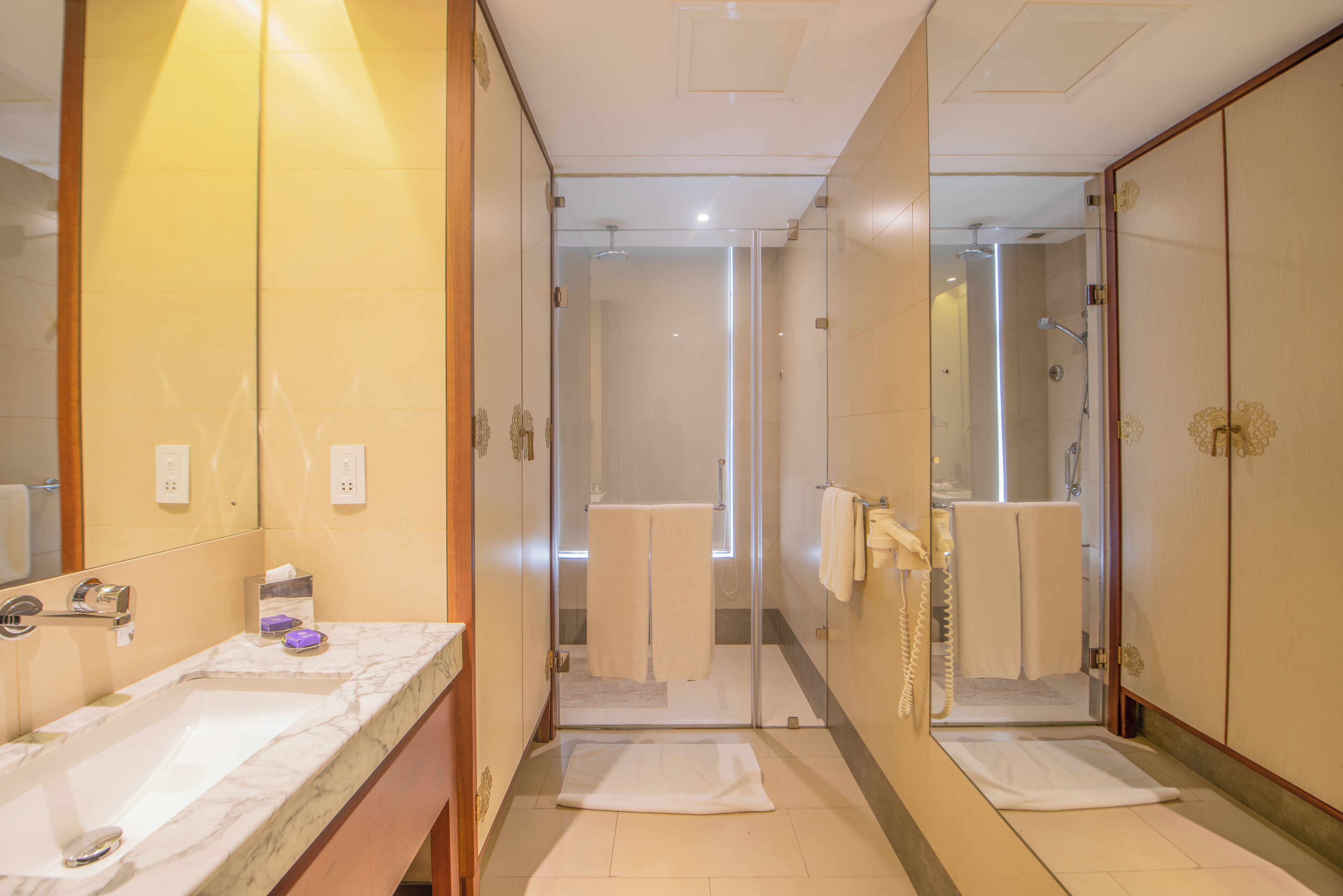 Un baño de hotel con un espejo grande, un lavamanos y una zona de ducha.
