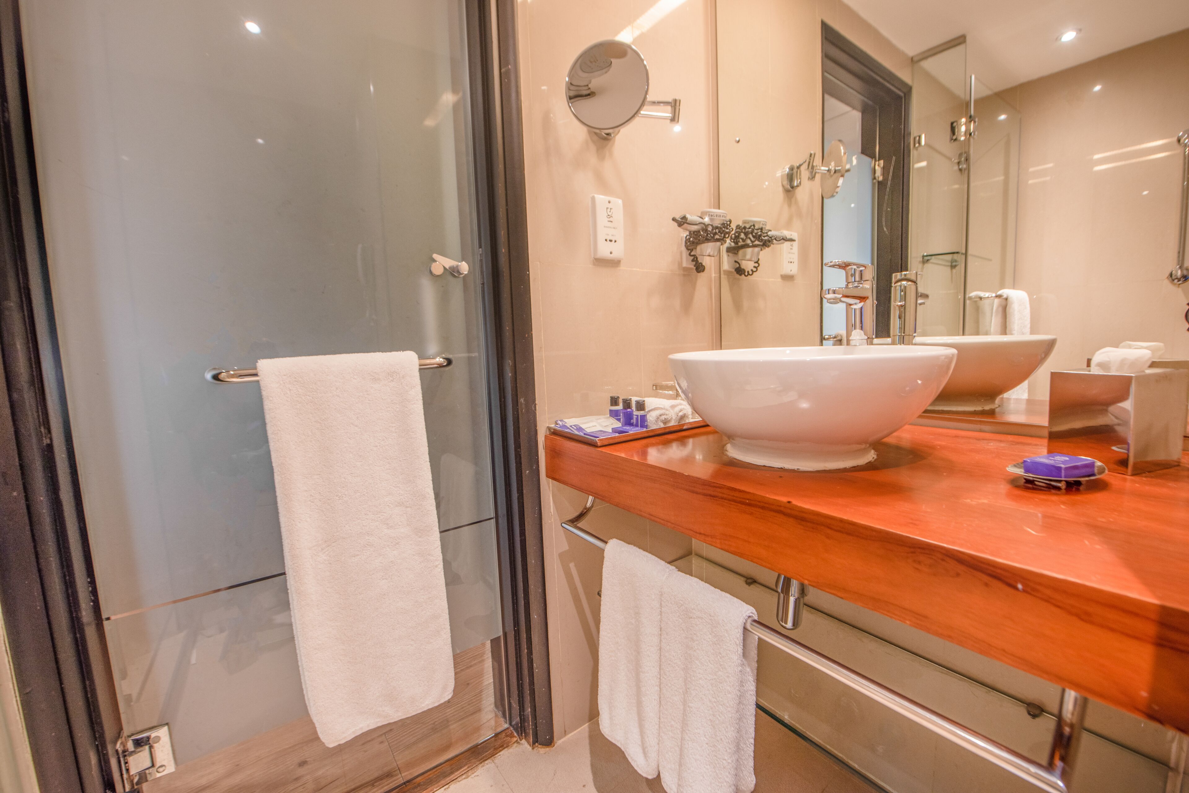 A modern bathroom with a large mirror, a white sink, and a glass shower enclosure.