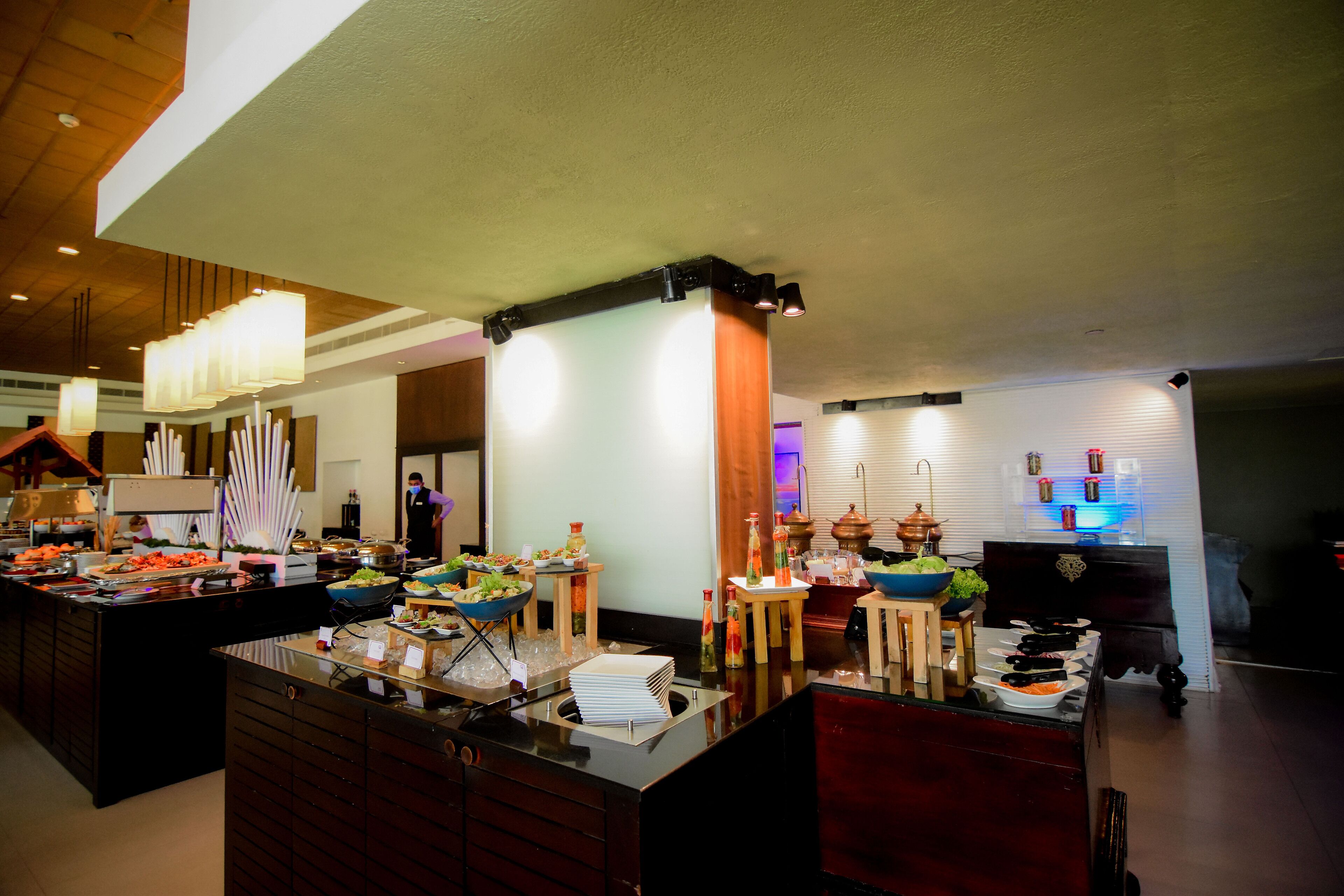 Mesa de buffet con diversos alimentos y una persona al fondo.