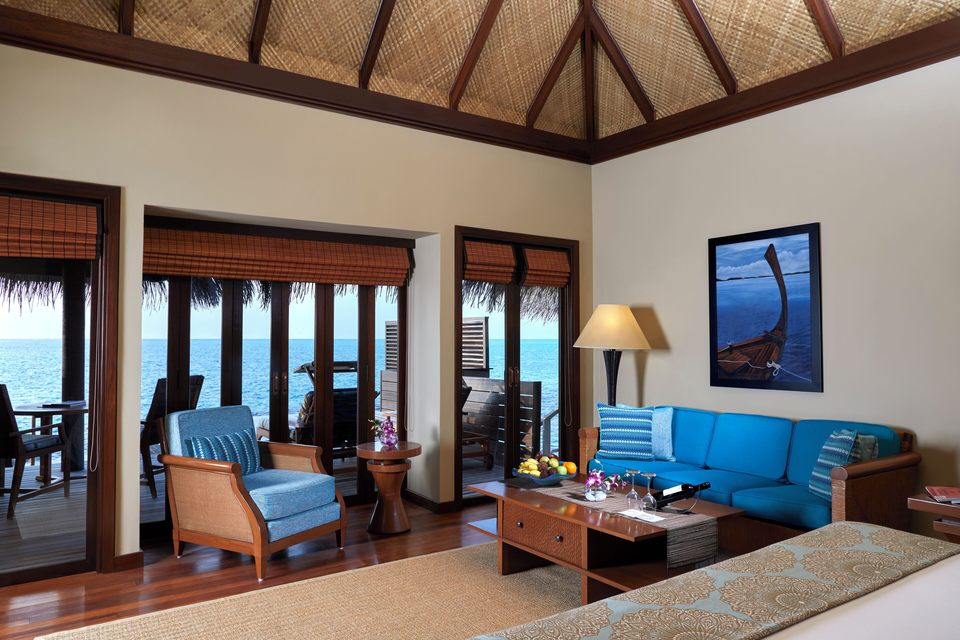 A room with a sofa, chairs, a coffee table, and a view of the ocean.