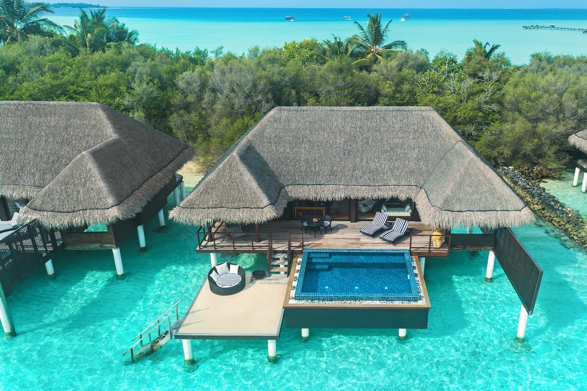 Wasserbungalows mit Reetdächern, einem Pool und Blick auf den Ozean.