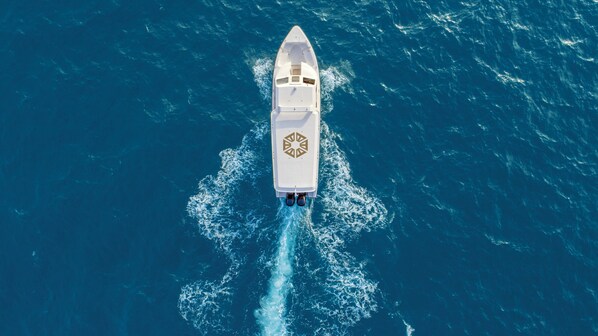 Un yate blanco con un logotipo distintivo en la cubierta, navegando sobre un océano azul intenso.