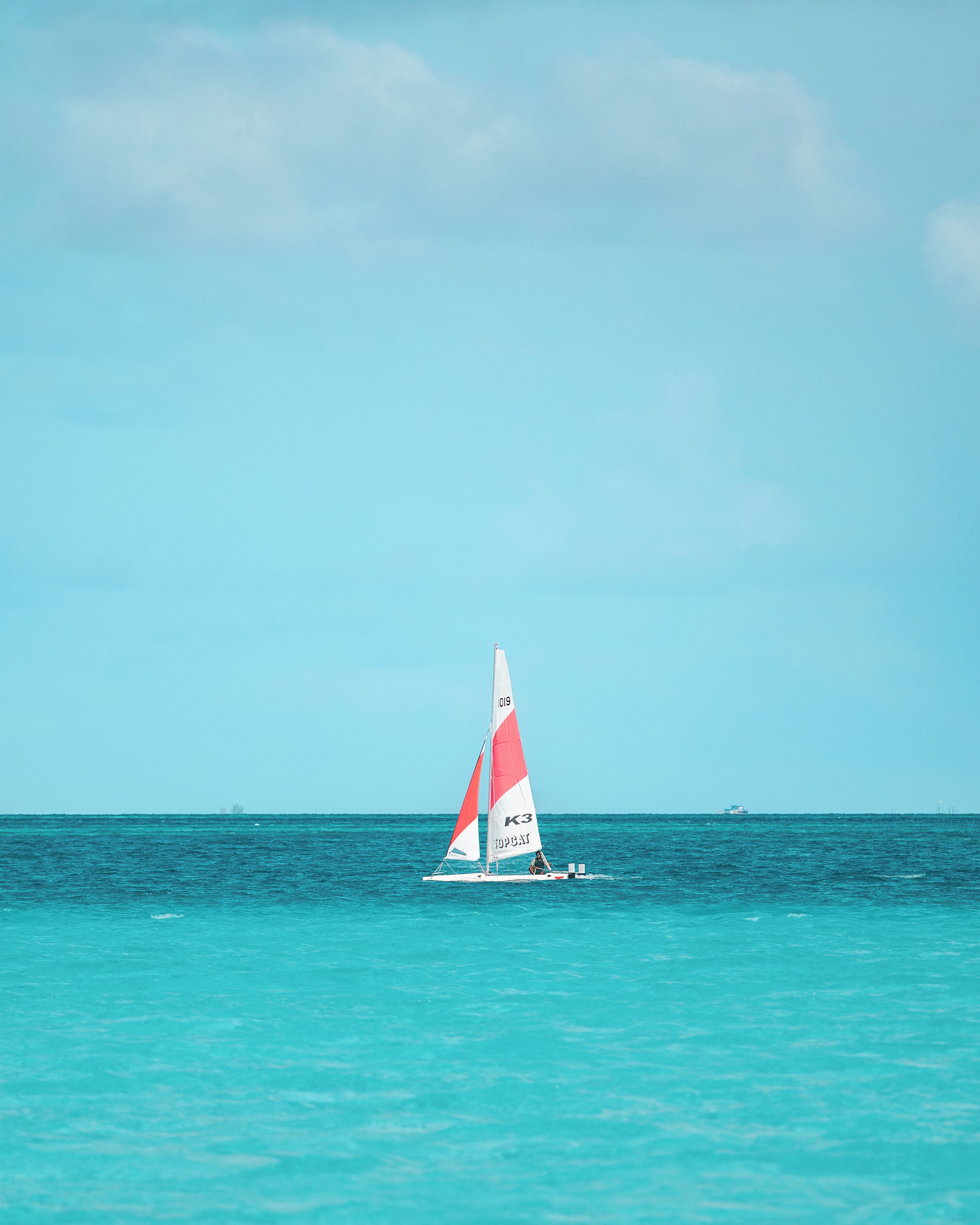 A sailboat on turquoise water with a clear sky.