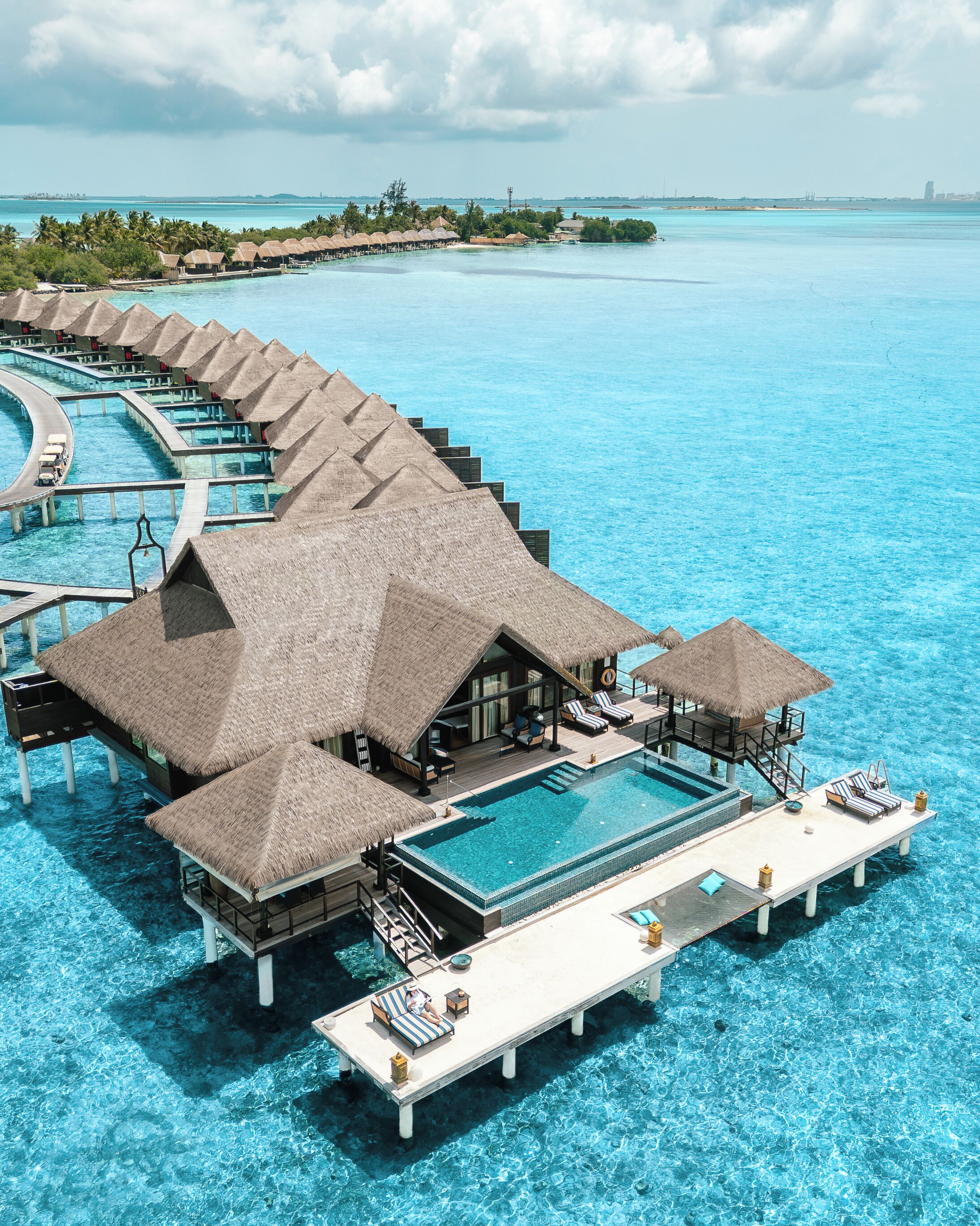 Bungalows over vandet med uendelige pools, et loungeområde og udsigt til havet.