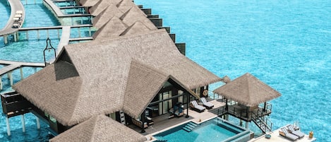 Bungalows over vandet med uendelige pools, et loungeområde og udsigt til havet.