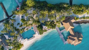 An aerial view of a resort with multiple swimming pools, palm trees, and a beach area.