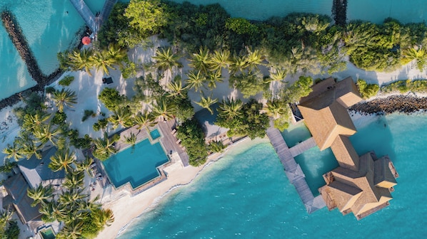 Vista aérea de un resort con varias piscinas, palmeras y una zona de playa.