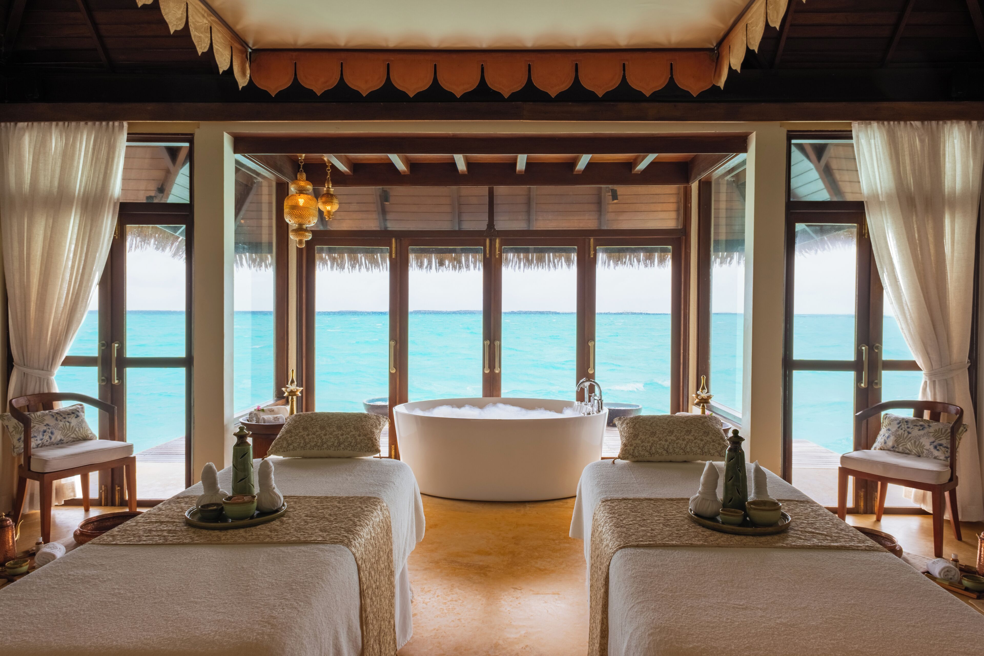 A room with a large bathtub, two beds, and a view of the ocean.