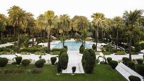 A large outdoor swimming pool surrounded by palm trees and well-manicured lawns. - Taj Mahal Lucknow (Lucknow)