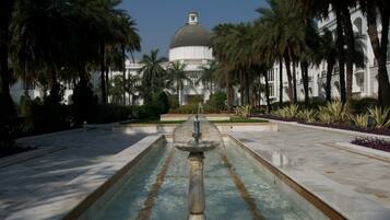 A fountain in the center of a courtyard with a large building in the background.