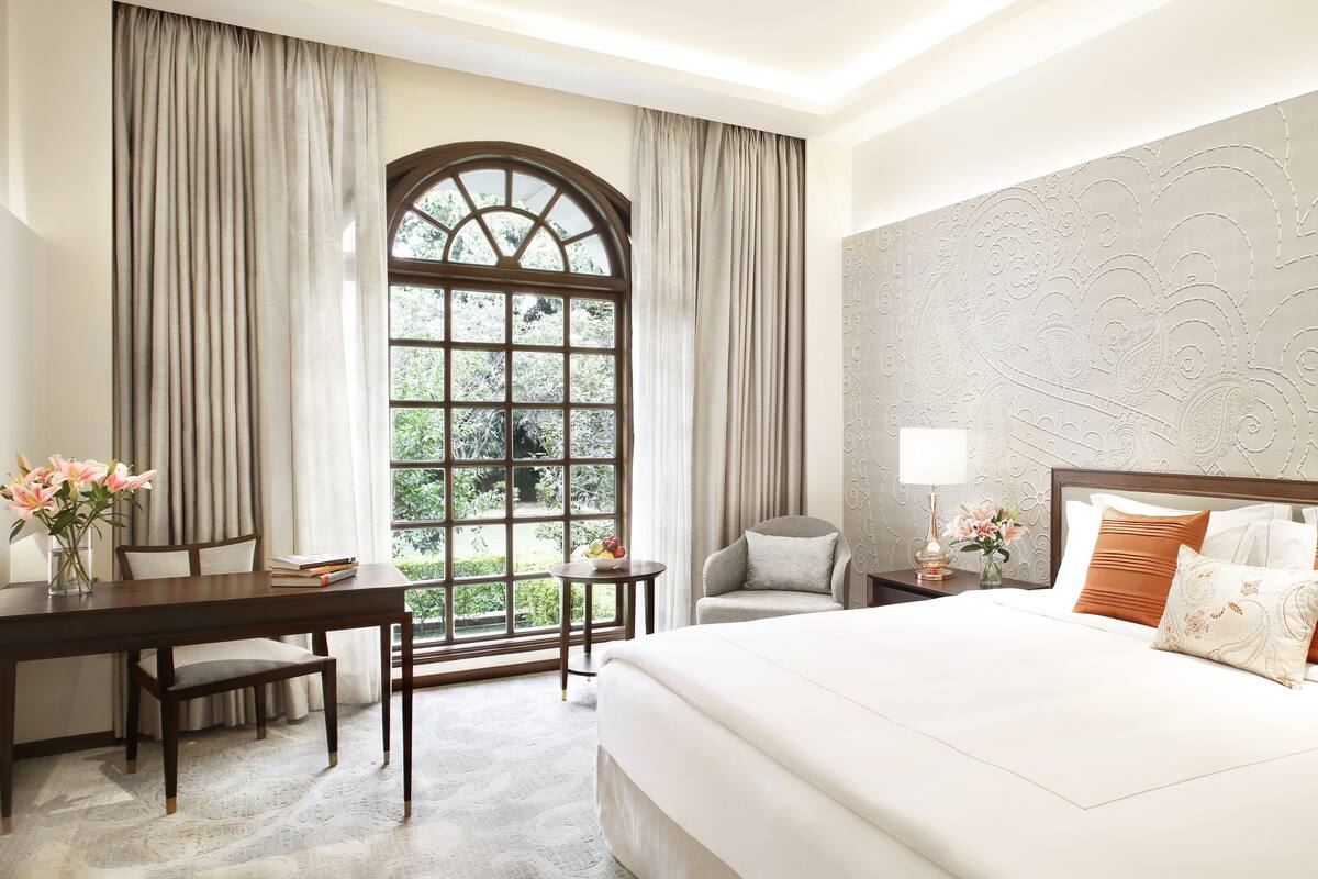 A hotel room with a large bed, a desk, and a window with curtains.