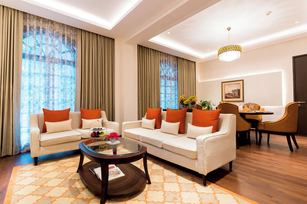 A modern living room with a sofa set, a coffee table, and a dining area with chairs and a table.