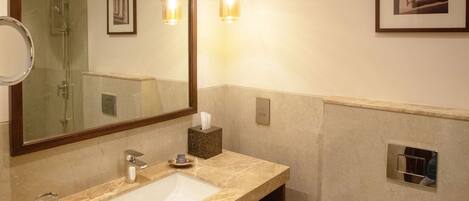 Un baño con un espejo grande, dos lavamanos, un inodoro y una ducha.