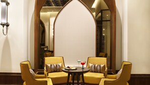 A room with a high arched doorway, a round table with two chairs, and a decorative lamp. - Taj Mahal Lucknow (Lucknow)