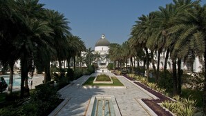 A grand building with a large dome, surrounded by palm trees and a central water feature. - Taj Mahal Lucknow (Lucknow)