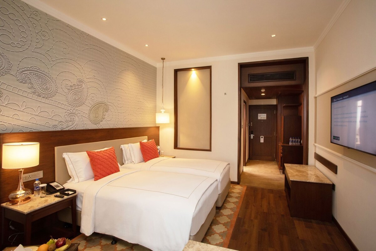 Ein Hotelzimmer mit Bett, Nachttisch, Lampe und Fernseher.